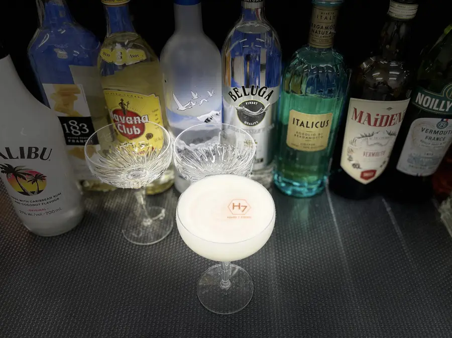 Bar spirits and a creamy cocktail in a coupe glass