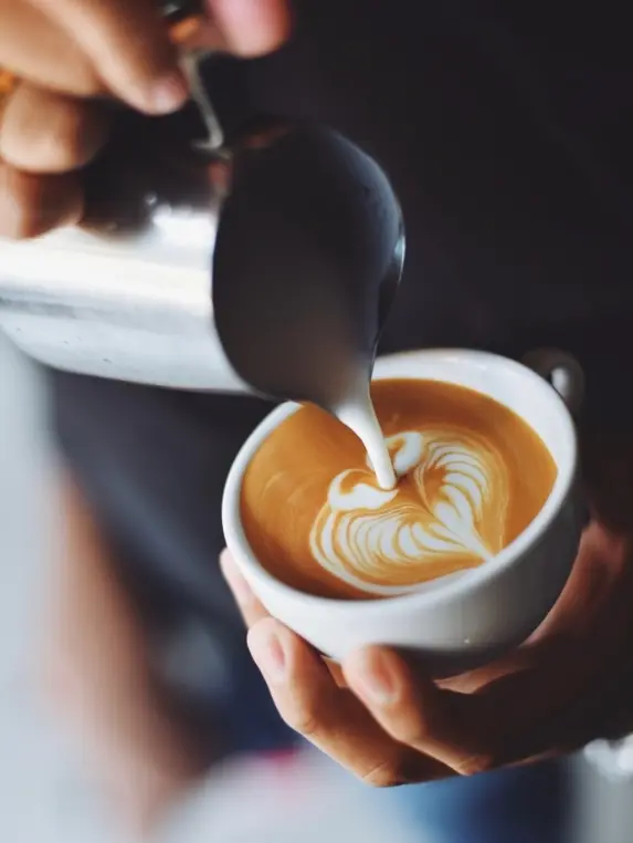 Barista pouring latte art into a cappuccino