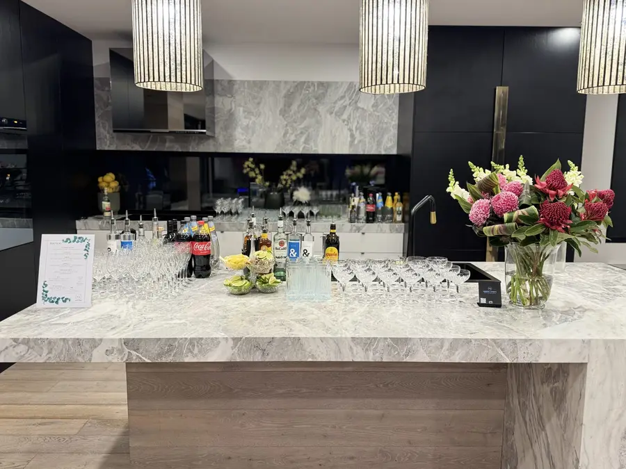 Cocktail bar set up on a marble kitchen island with flowers