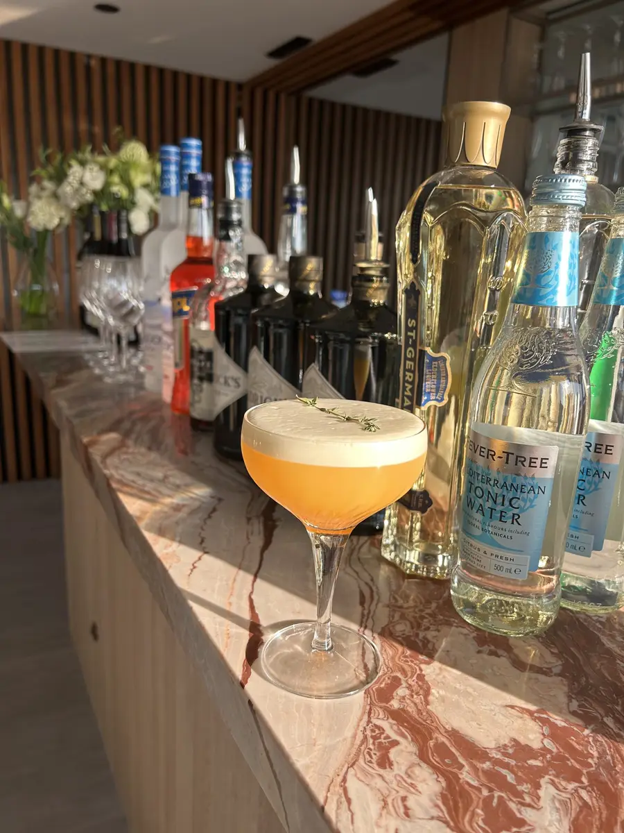 Cocktail bar with spirits and a whisky sour on a marble counter