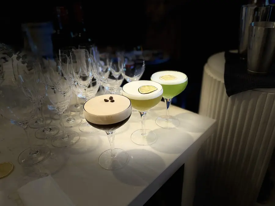 Espresso martinis and green cocktails lined up on a bar