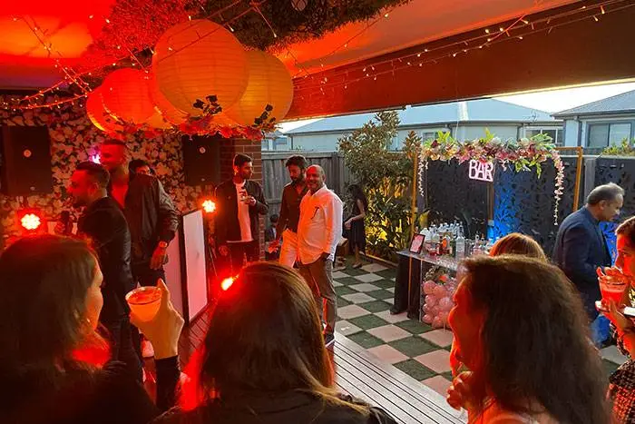 Guests at a housewarming party under red festoon lights