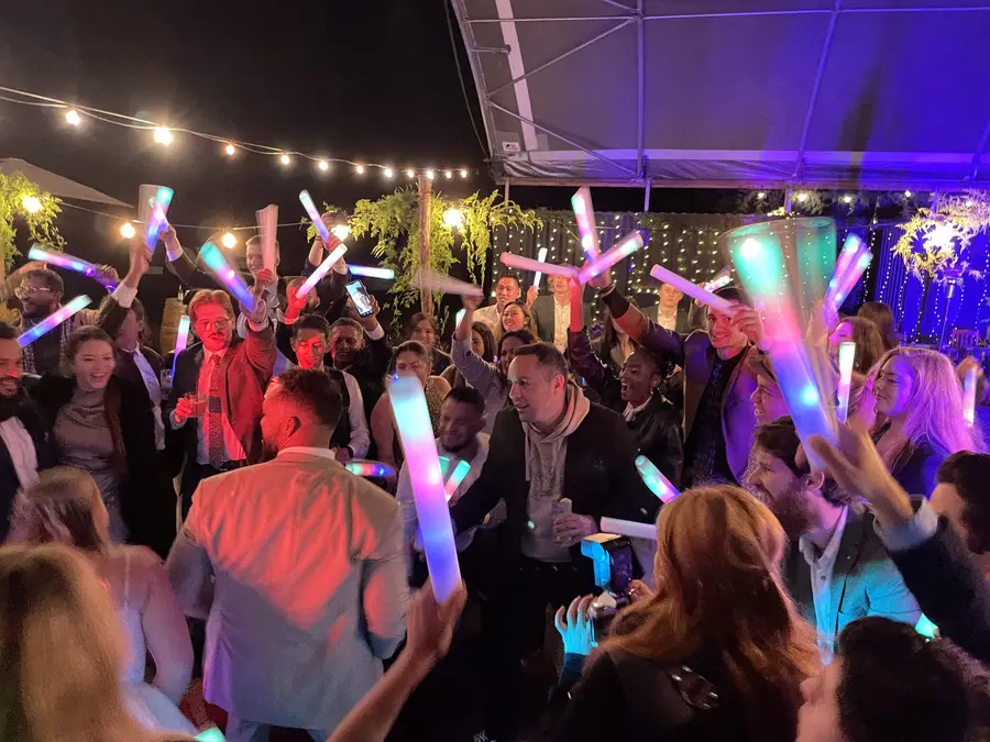 Guests dancing with glow sticks at a night-time party