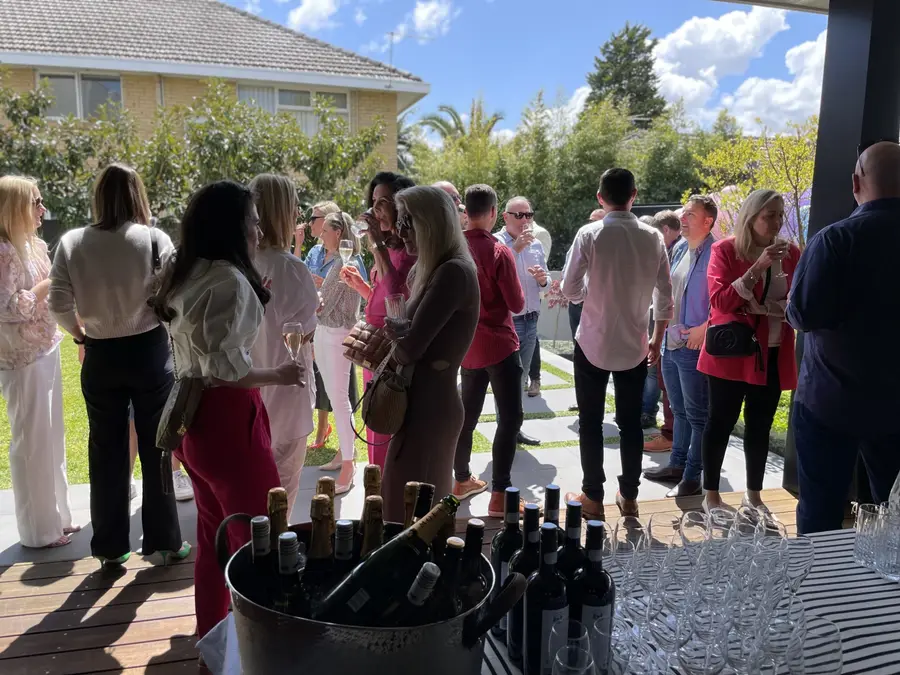 Guests mingling at an outdoor garden party with a wine and drinks station