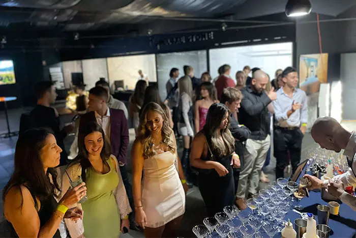 Guests mingling with drinks at a birthday party in a warehouse venue