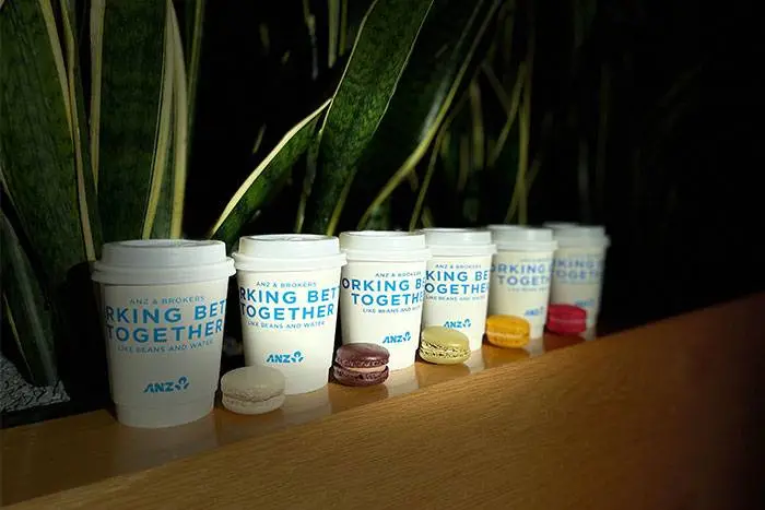 ANZ branded coffee cups and macarons at a corporate event