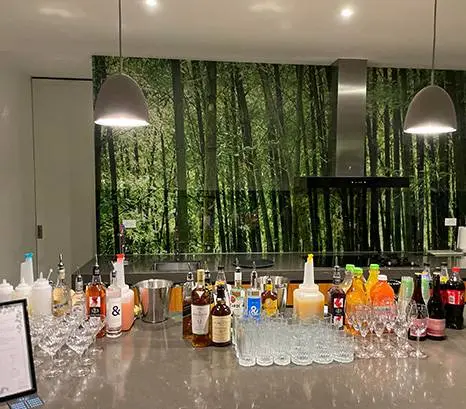 Home bar on a kitchen bench with spirits, mixers and glassware for a housewarming party