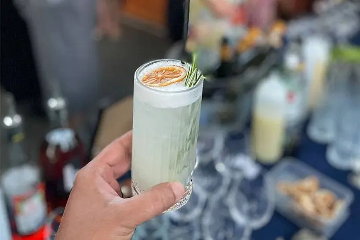 Garnished cocktail held up at a housewarming party