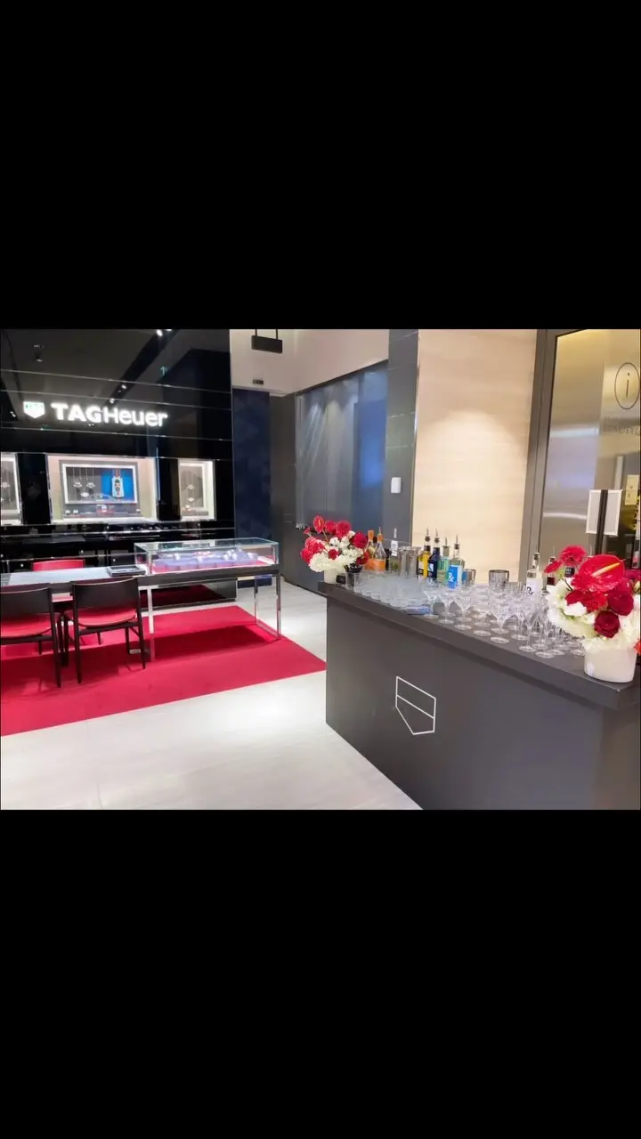 A mobile bar with spirits and red flowers set up inside the TAG Heuer boutique