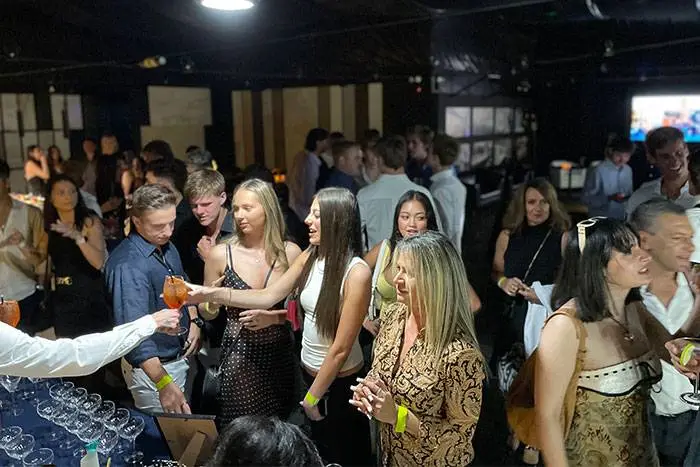 Guests raising drinks at a busy private party bar