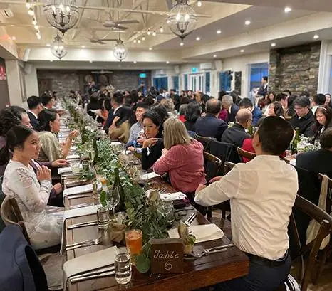 Wedding reception guests seated at long tables under chandeliers