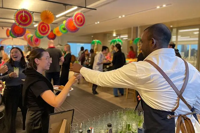 Bartender serving a drink at a colourful office welcome party