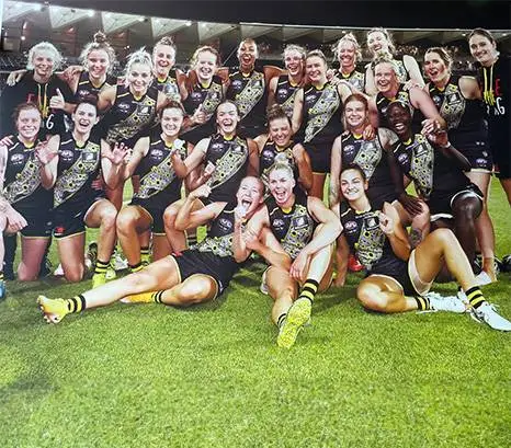 Women's football team celebrating on the ground after a win