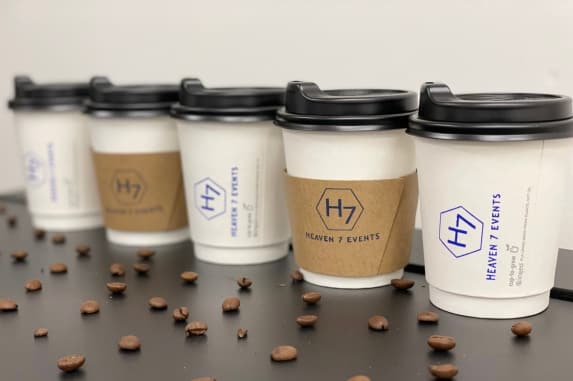 Row of Heaven 7 Events branded takeaway coffee cups with coffee beans